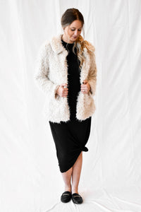 Model wearing women's cream colored teddy fur coat with snap buttons.