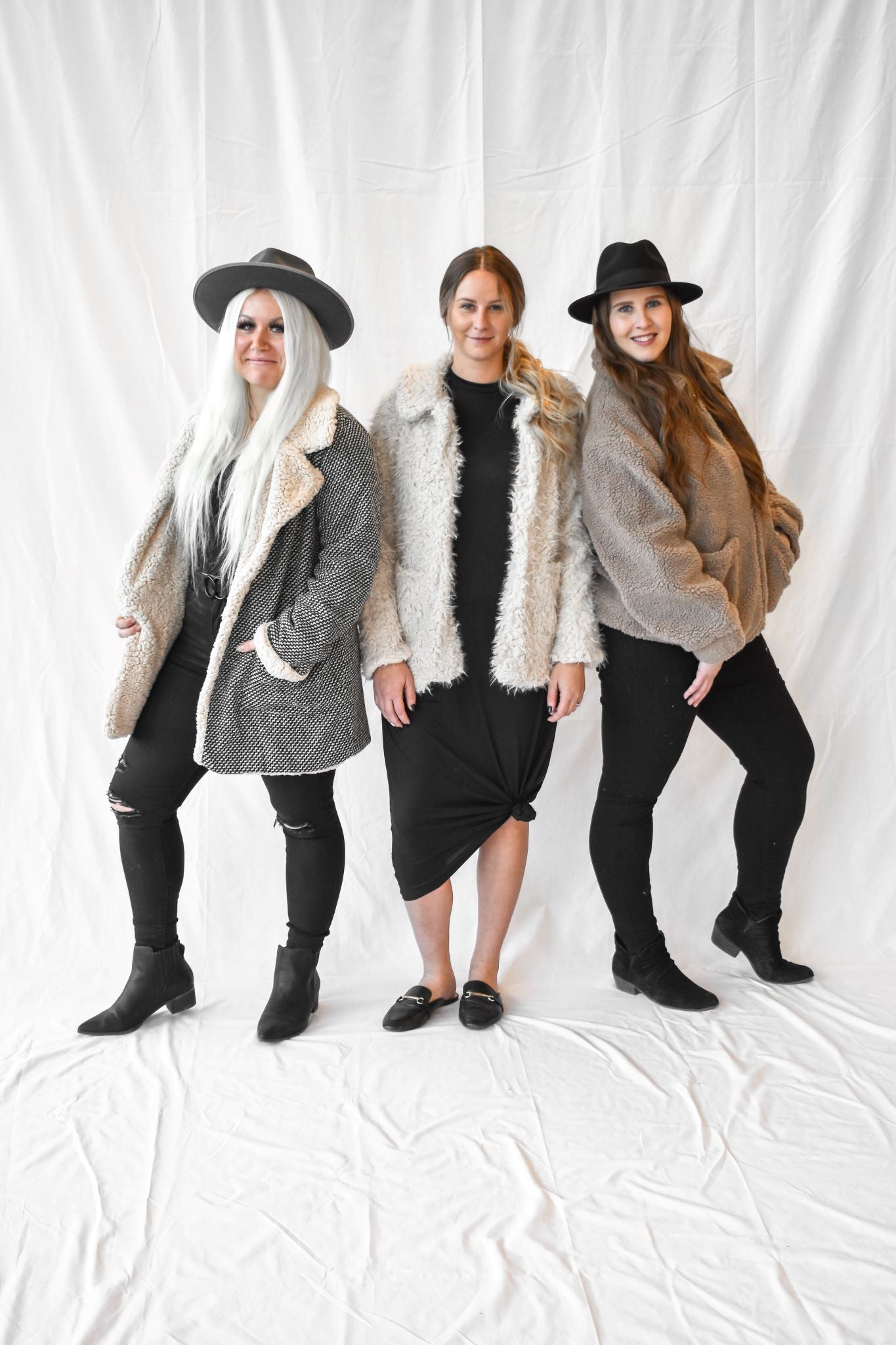 Model wearing women's cream colored teddy fur coat with snap buttons, with other models in faux fur lined coat, and brown fur jacket.