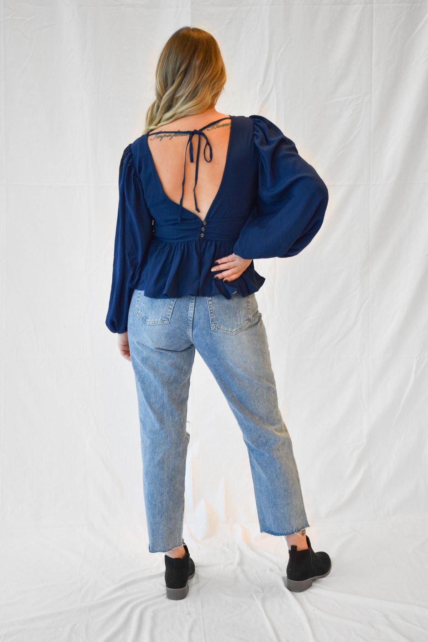 Model wearing women's navy blue long sleeved V-neck peplum top.