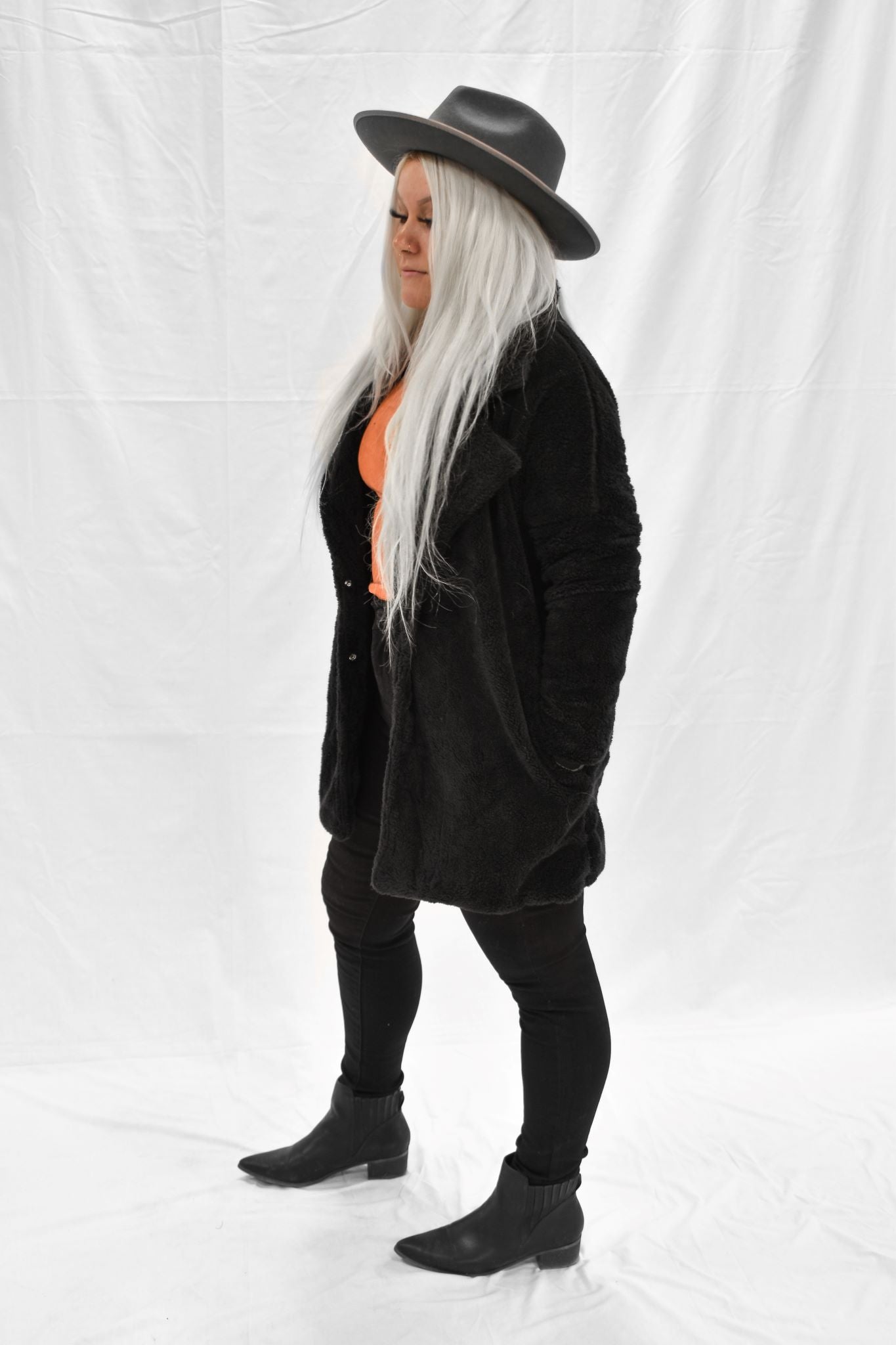 Model wearing women's black fur coat with snap buttons.