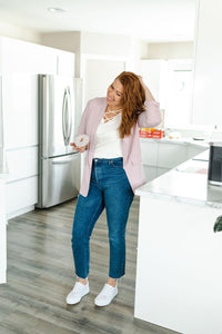 Model wearing a women's light pink blazer paired with jeans. 