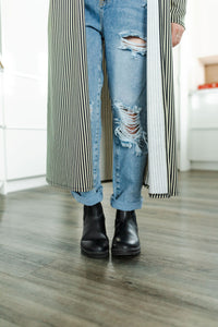 Model wearing women's light wash high waisted straight jeans with cropped bottoms paired with long striped cardigan.