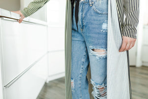 Model wearing women's light wash high waisted straight jeans with cropped bottoms, paired with long striped cardigan.