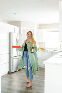 Woman at home wearing sage green long fleece jacket.