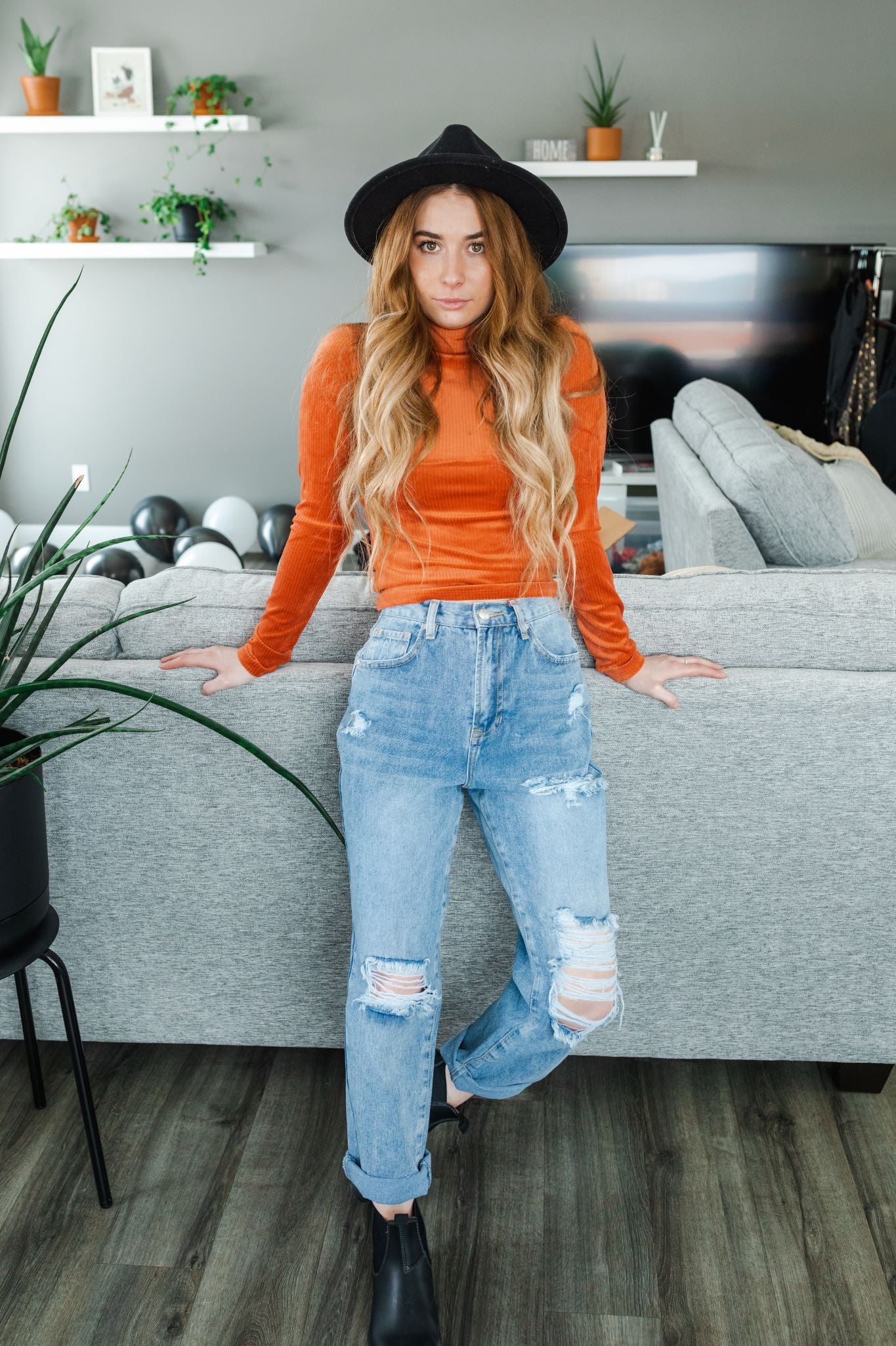 Model wearing women's orange/ terracotta  velvet ribbed mock neck cropped top with long sleeves.