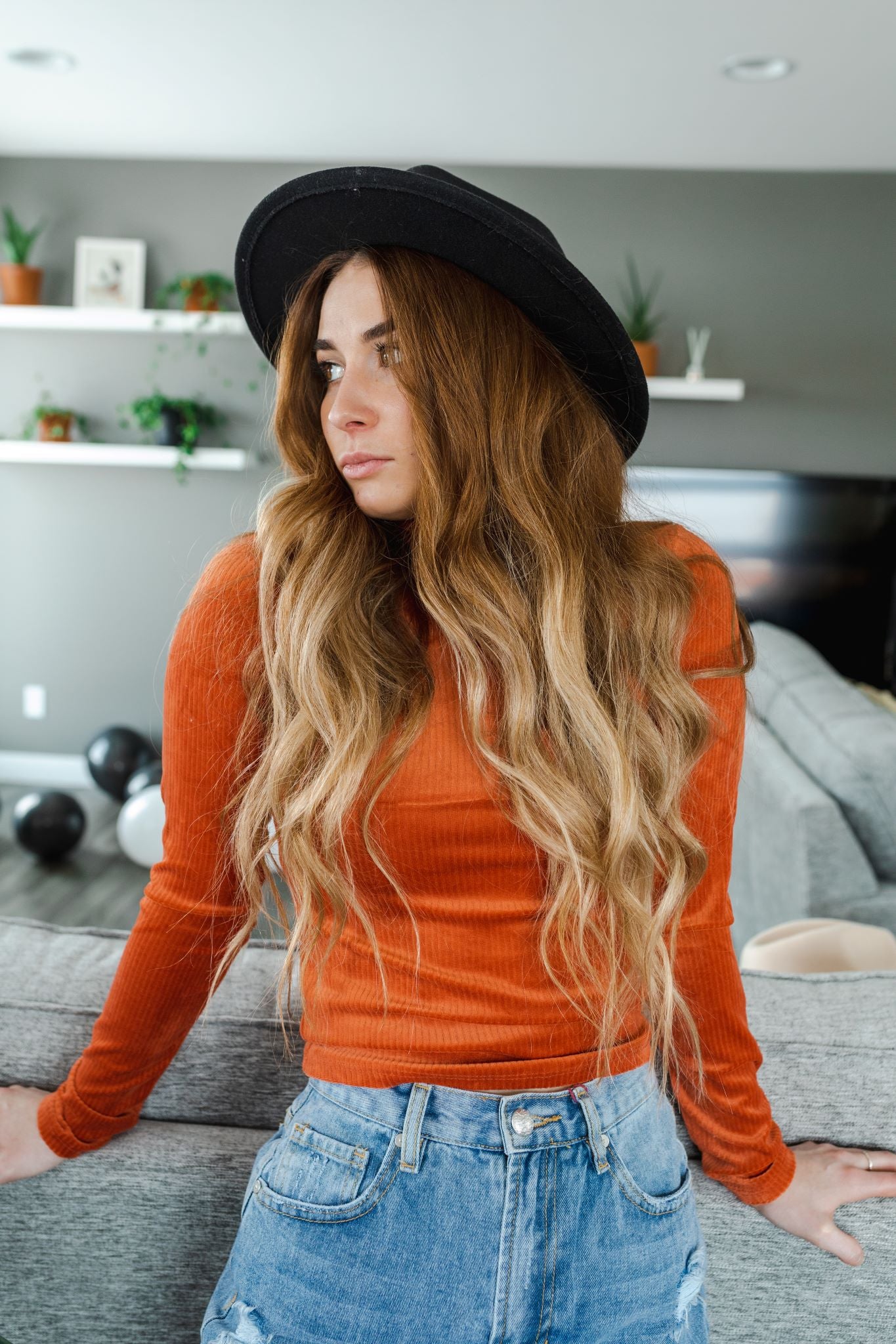 Model wearing women's orange velvet ribbed mock neck cropped top with long sleeves.