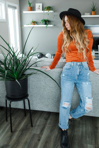 Model wearing women's light wash high waisted straight jeans with cropped bottoms.